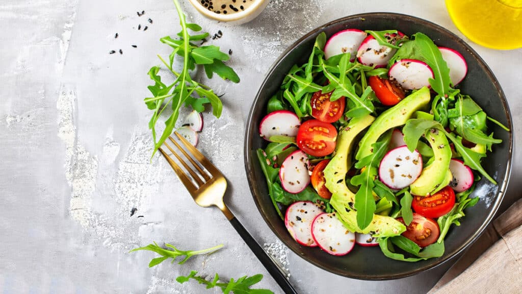 healthy salad with tomatoes and avocados in a bowl on a table