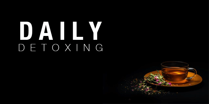 cup of tea on a gold plate against black background with "DAILY DETOXING" written next to it